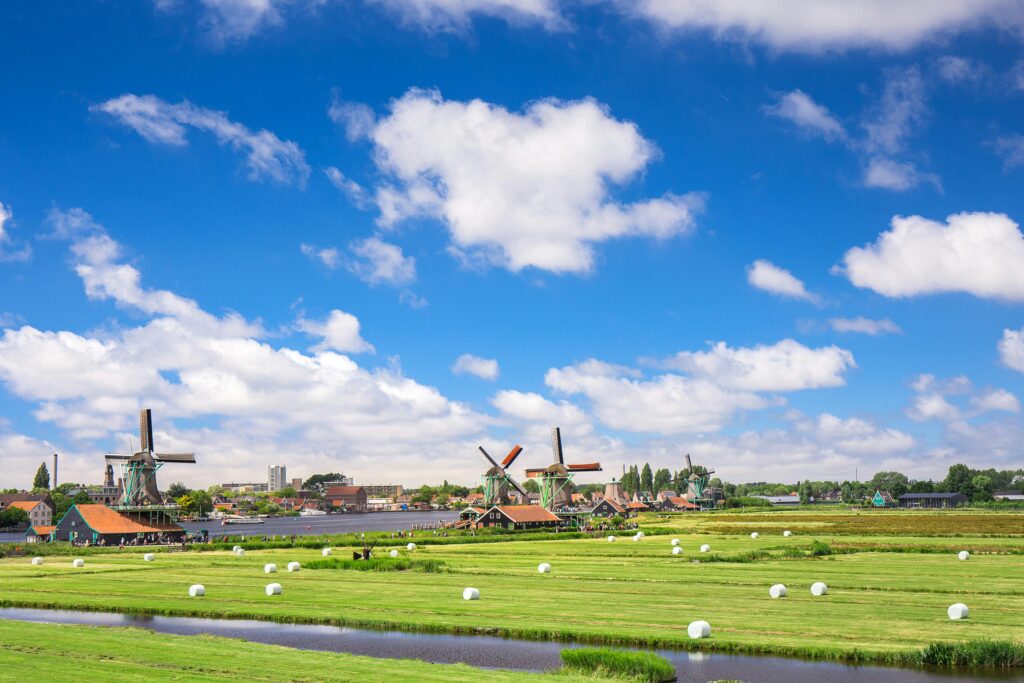 Picturesque view of traditional windmills and farmland in rural Amsterdam under a clear blue sky.